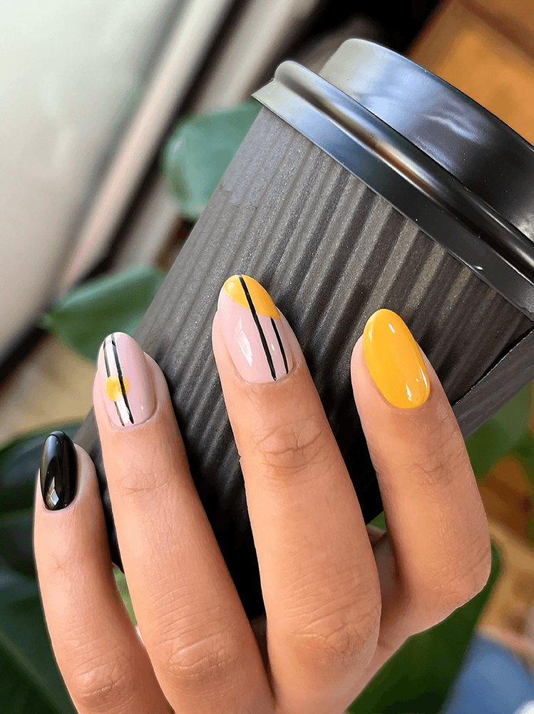 Hand showing nail art in yellow, black and tan