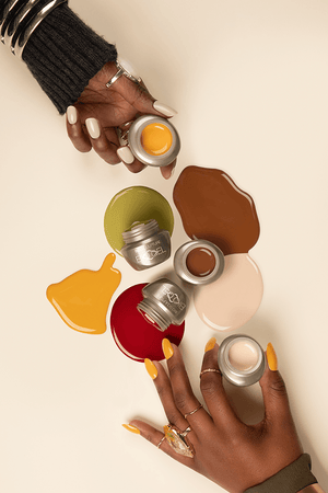 A close-up of a person's hands holding small jars of Biogel gel colors